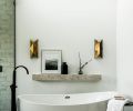 n the main bathroom, a custom mirror treatment designed by Kowalski is lit with Hudson Valley sconces.
