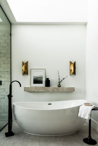 n the main bathroom, a custom mirror treatment designed by Kowalski is lit with Hudson Valley sconces.