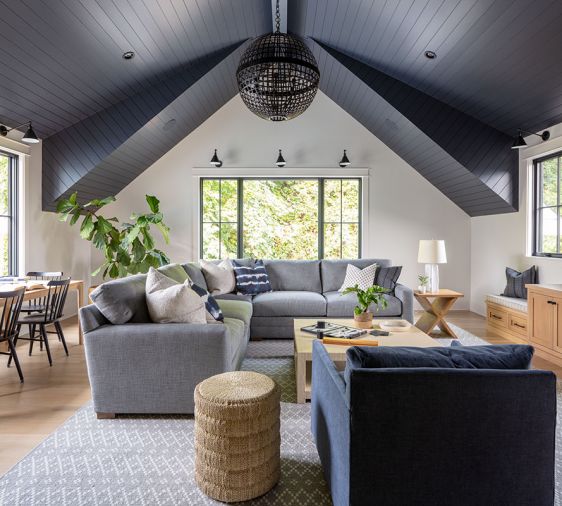 The dramatic vaulted ceiling in the bonus room is painted Benjamin Moore Baby Seal, and adorned with a light fixture from Visual Comfort. Stroud covered the Lee Industries sectional and chair with JAB fabric from the Dixon Group at the Seattle Design Center. The coffee table and side table are from Serena & Lily.