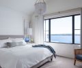 The main bedroom is softened with custom window coverings, including curtains composed of Pindler & Pindler linen fabric, and a shade with Schumacher trim from The Dixon Group.