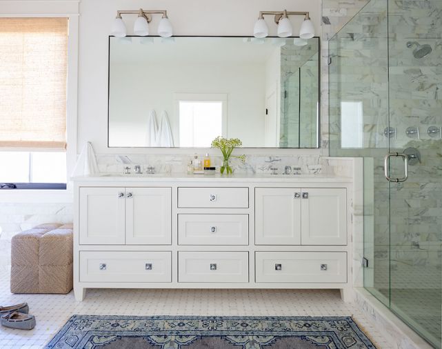 The main bathroom is now wrapped in 3x6 Calacatta marble tile by Ann Sacks, in a wainscot behind the Signature Hardware tub and vanity, and in the walk-in shower. The overhead and sconce lighting is by Visual Comfort. Stroud designed the vanity with Waterworks hardware.