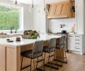 In the kitchen, custom white oak cabinetry bedecked with Restoration Hardware pulls feels furniture-like in the new open plan. A generous island is topped with creamy Pental quartz, and has Lawson Fenning stools tucked beneath. The custom white oak stove hood is the focal point.