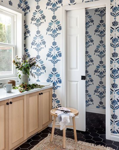 The Hygge & West wallpaper is a “conversation starter,” says Lars. The pattern enfolds the new mudroom and powder room behind the pocket door. Custom white oak cabinets sync with the kitchen, and black floor tile, from Statements Tile, is chic and durable.