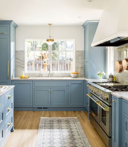 Above the new sink, large windows overlook the backyard and provide an easy pass-through to a small outdoor kitchen area. Ray creates visual calm in the small space by encasing large appliances. Here a Sub-Zero freezer to the left of the sink is camouflaged and then balanced by the taller storage cabinet on the right.