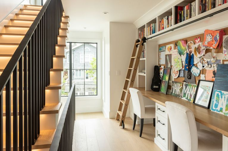 A wide hallway for stairs leading to third floor was carved out of primary bedroom to provide dual desk with wrap-around storage for books, art projects, and homework – sliding library ladder included. Williams Sonoma chairs.