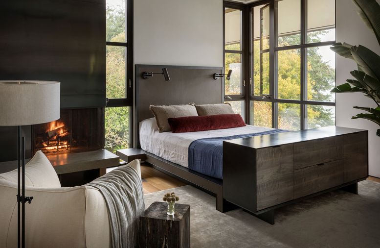 Steel fireplace in primary bedroom includes concrete hearth. Custom Geremia leather and steel bed co-designed with fabricator Todd Von Martens. Workstead floor lamp teams with vintage Pamono club chair.