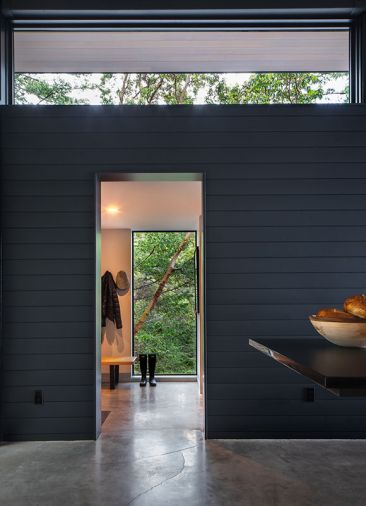 The mudroom and pantries are tucked behind a wall of clear cedar channel siding, and the floors are concrete.
