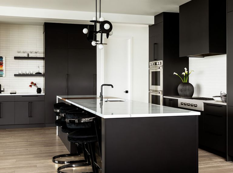 Clean lines and loft-inspired colors and fixtures ground and define the kitchen in what otherwise might have felt like a cavernous space. Contemporary lighting from Kelly Wearstler’s architectural Nodes line is used throughout the home, including a statement chandelier over the kitchen island. Glossa and Kestenbaum’s skill with space planning resulted in high-functioning spaces for enthusiastic home cooks and entertainers. Sleek cabinetry frame Wolf appliances and a concealed Vent-A-Hood. The oversized island features a built-in walnut cutting board from Cross Cut Woodworks and a dramatic waterfall countertop of PentalQuartz.