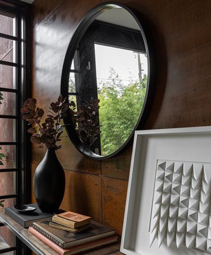 Corten steel burnishes entry. White art entitled “Sweep” by Dave Crawford. Black circular mirror plays off painted black Marvin Contemporary windows aluminum exterior and hefty vault-style Fleetwood entry door.