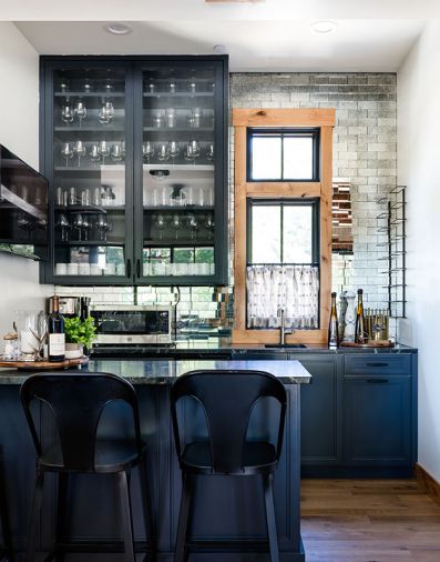 Tucked in an alcove off the kitchen, the bar has more dramatic finishes, like the antiqued mirror tile, “Dutchess” by Bedrosians, and cabinetry painted Benjamin Moore “Midnight Blue.”