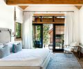 The tongue-and-groove wood ceiling in a bedroom seamlessly matches the exterior porch ceiling for continuity between inside and out.