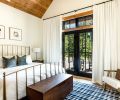 The bedrooms all received custom blackout window treatments from Shades of Elegance. Here, a Crate & Barrel bed frame was placed with a CB2 trunk and Annie Selke rug, the latter from J Garner Home.