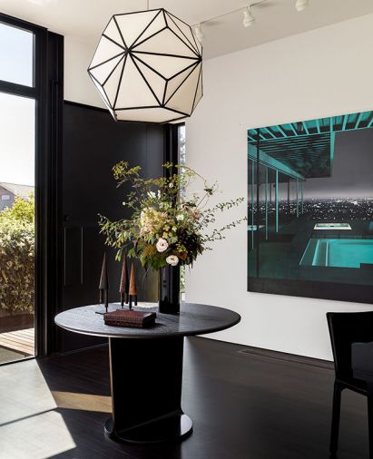 In the entry, a light fixture by Erich Ginder, made of die-cut linen stretched over a laser-cut plywood frame, hangs over the clients’ table. The painting is by Laurence Jones.