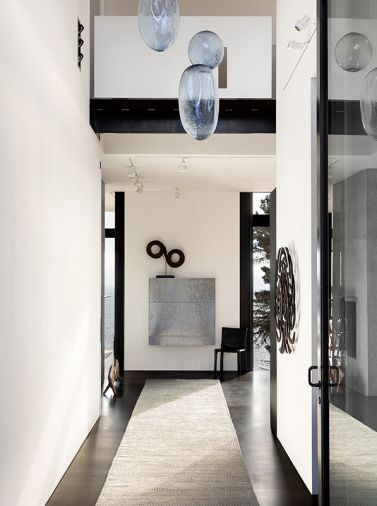 A custom runner by Stark Carpets runs the length of the hall, with Ann Gardner’s “Bubbles” sculptures beautifully reflecting light overhead. The wall-mounted piece at the end of the hall is the owner’s custom desk.