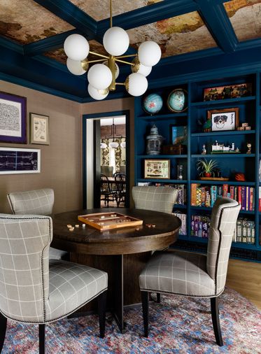 In the games room, a Theodore Alexander table from DFG at the Seattle Design Center sits with CR Laine chairs. Custom shelving, designed by Rowland and built by Superior Cabinets, is painted a blue hue by Benjamin Moore, to sync with the sepia tones of the Schumacher map wallpaper above. The artwork is from the homeowners’ collection, reflecting their love of travel. “Rebecca is kind-of magic,” says Frederica, of how the designer threads elements together.