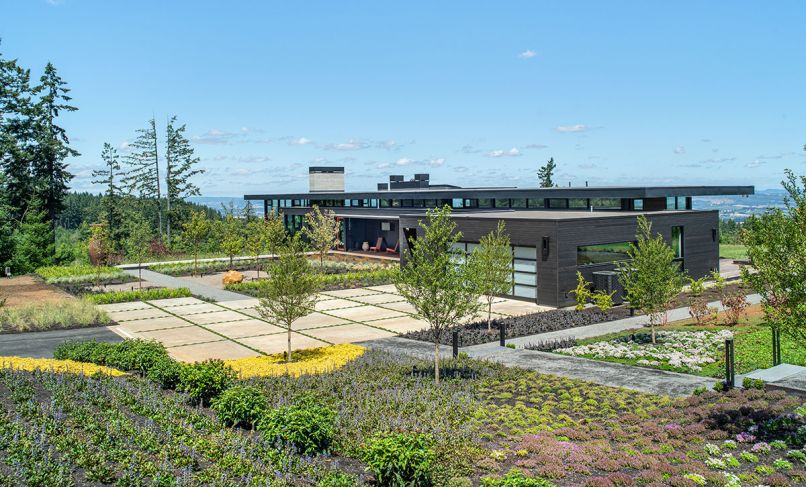 This 4,500-square-foot home on 40 acres in the Chehalem Mountains was completed in 2020 by Scott Edwards Architecture and iBuildPdx, for owners who wanted to celebrate the site, make art, and retreat from city life. Its stunning views of several mountains earned its name as the Five Peaks Lookout. The landscape design was led by Shapiro/Didway, who created a modern, geometric entry court in front that leads to an orange Fleetwood door. The exterior siding is from Lakeside Lumber. Photography © Peter Eckert