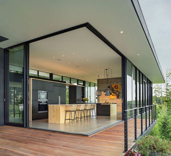 A glass-walled cantilever maintains transparency with the surrounding landscape. The ground cover on the slope beneath is “its own architectural feature,” says project manager Aaron West of Shapiro/Didway. The main living spaces are in the cantilever, with Fleetwood sliders opening a corner to the outdoors. “It’s kind of like you’re walking on the top of one of those mountains that you’re looking at,” says interior designer Cameron Cruse, of the view from inside the house. Photography © Peter Eckert