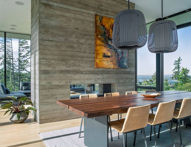 A double-sided fireplace in the board-formed concrete chimney column both separates and unites the living and dining rooms. Photography © Peter Eckert