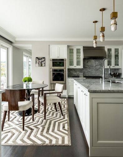 Visual Comfort pendants add organic, contemporary element to existing kitchen. Theodore Alexander dining chairs echo contrasting shades of graphic Kyle Bunting rug. Design Within Reach marble oval table reiterates shape of DR chandelier.