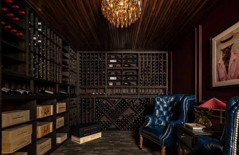 The properly constructed wine room features a slatted oak ceiling, porcelain floor pavers, a custom Rhino Wine Cellars wine racking system and a dedicated ventilation system. Restoration Hardware chandelier adds Regency touch. Moody Cup O’ Java Benjamin Moore paint. Vigilant Humidor between English Elm wingbacks.