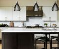 In the kitchen, marble mosaic tile from Ann Sacks covers the backsplash, joined by Benchmark Custom Cabinets and Caesarstone 4120 Raven on the perimeter counter. The stove hood is by Wolf and the Bensen island stools are from Inform Interiors.