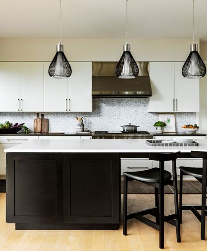 In the kitchen, marble mosaic tile from Ann Sacks covers the backsplash, joined by Benchmark Custom Cabinets and Caesarstone 4120 Raven on the perimeter counter. The stove hood is by Wolf and the Bensen island stools are from Inform Interiors.