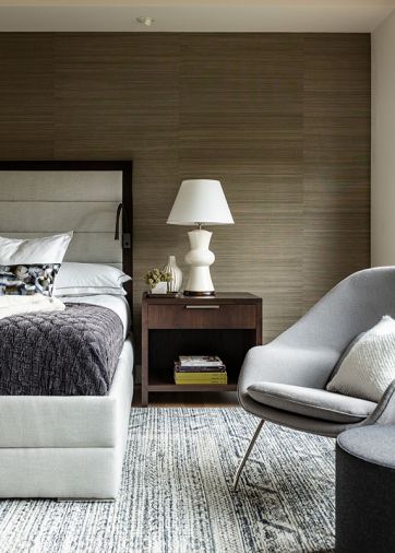 n the primary bedroom, a textural Kneedler Fauchere wallcovering offsets the custom bed frame, with a custom rug from Driscoll Robbins and a Saarinen-style Womb chair through Modern Classics Furniture bringing modern coziness.