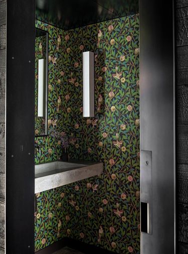 Powder room at right of entry features William Morris ‘Bird & Pomegranate’ wallpaper. Stefan Gulassa sconce with layered transparent laminated paper. Fluid Concrete sink drains off linear pipe at sink back to not take attention from wallpaper. 
Photography © Haris Kenjar