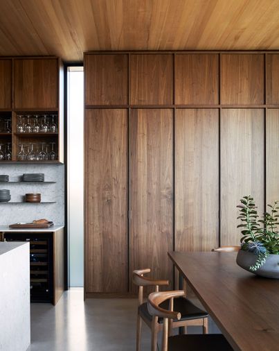 GO’C designed custom walnut cabinets built by Scott Faulkner gracefully rise to meet the clear cedar ceiling - a testament to Thomas Fragnoli Construction’s ability to create custom vents hidden above cabinets that promote a seamless look to the character of the house. DWR Wishbone Dining Chairs add graphic appeal to Faulkner’s custom dining table.