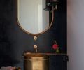 Powder Room’s custom brass sink designed by GO’C and built by Alpine Welding set against dramatic dark blue plaster walls and Allied Maker pendant. SP01 Design Michelle mirror.