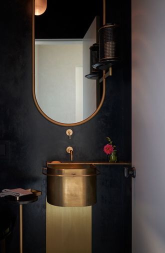 Powder Room’s custom brass sink designed by GO’C and built by Alpine Welding set against dramatic dark blue plaster walls and Allied Maker pendant. SP01 Design Michelle mirror.