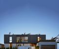 “On the north street view of Sound House, the architecture offers privacy and protection through site walls and wood screens,” says Gentry. Custom wood screens with ebony stain frames the bridge between kids and primary wings. Corten Steel door pops against stucco finished garage. Custom Corten steel planters adorn garage roofing. Richlite trim panels above and below windows. Exterior plaster on main level.