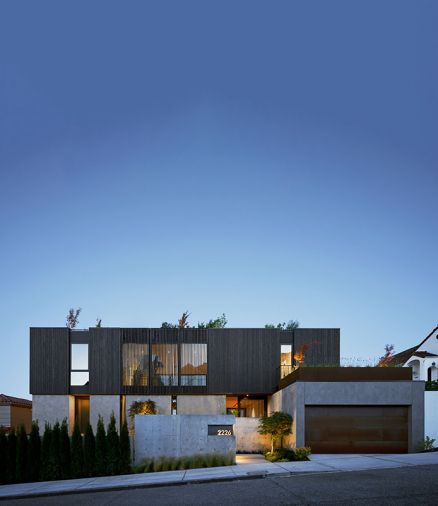 “On the north street view of Sound House, the architecture offers privacy and protection through site walls and wood screens,” says Gentry. Custom wood screens with ebony stain frames the bridge between kids and primary wings. Corten Steel door pops against stucco finished garage. Custom Corten steel planters adorn garage roofing. Richlite trim panels above and below windows. Exterior plaster on main level.