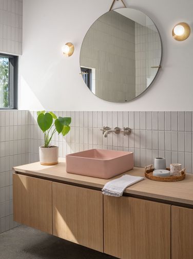 In the bathroom, a custom white oak vanity is bedecked with a pink Kast ‘Aria’ sink. The walls have ceramic tile from Fireclay, in 2x6 French Linen.