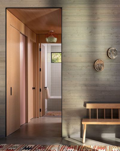 The rift-sawn white oak in the hall reveals a pink door to the laundry.