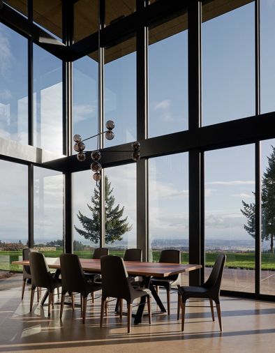 Dramatic dining room windows by Western Window System from Portland Millwork include awning window that opens before A/C is needed. Bontempi Casa dining table lit by PROF chandelier.