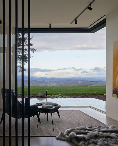 Main Level sitting room view of rolling hills/wine country through Andersen/Weiland pocket doors from Portland Millwork. Vertical screens frame Gorini Divani chair and Mobital side table.