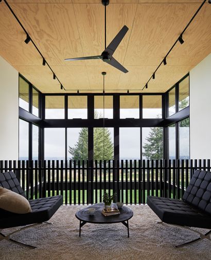 Piano room on mezzanine overlooks dining room, drawing eye to dark Modern Fan Company fixture adding contrast to stained plywood ceiling panels. Oscar coffee table grounds scene.