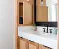 While the consul in the powder room is prefab, and the sink and vanity in the primary bath are custom, both feature white oak for consistency.