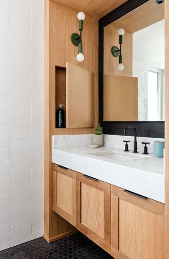 While the consul in the powder room is prefab, and the sink and vanity in the primary bath are custom, both feature white oak for consistency.