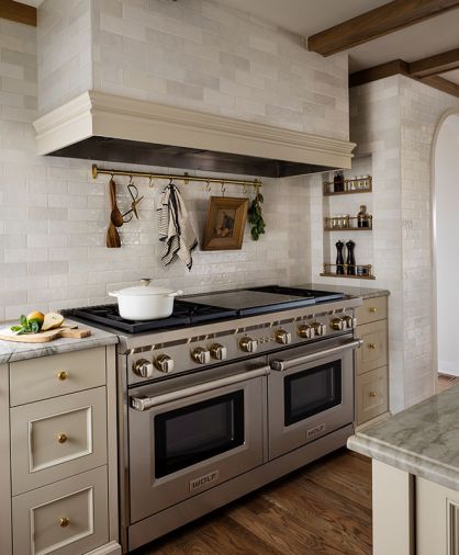 Interior designer Kat Lawton transformed this Mercer Island kitchen so it not only functions better, but suits its Tudor-style surroundings. Details make the difference, like an inset, tiled niche for spices with a brass gallery rail system from Paxton Hardware and a utensil rail from Rejuvenation.