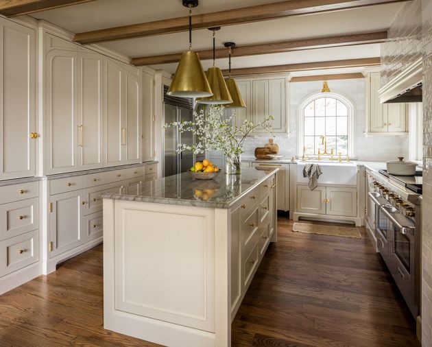 All of the cabinetry was designed by Kat Lawton Interiors and fabricated by Northwest Custom Interiors, with the face of the built-in appliance cupboard subtly reflecting a four-centered arch motif. The doors pocket for easy access to the interior. The cabinet color throughout is Benjamin Moore ‘Inner Balance,’ and the brass hardware is a mix of Rejuvenation and House of Antique Hardware.