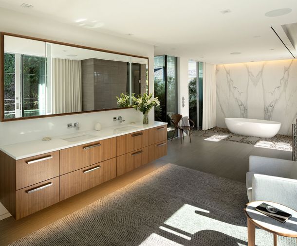 Third Floor primary bath features William/Kaven custom double walnut vanity with white polished Pental Quartz countertop, Graff Solar wall-mounted lavatory faucet. Seating area with Kush Rugs. Victoria & Albert tub on bed of river rocks. Calacatta Lincoln marble slab wall.