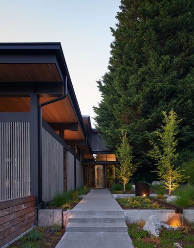 The entry sequence includes uplit gardens and a water feature, as well as a gate to the outdoor room.