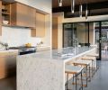 In the kitchen, sliding glass doors open the room to the covered outdoor space. The cabinetry was designed by Greg, whose parents had a kitchen cabinet business in Iowa, and built by Contour Woodworks. A Miele range, Dornbracht plumbing, Kelly Wearstler pendants, and Token barstools complete the scheme.