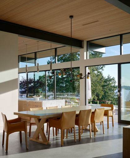 In the dining room, a Holly Hunt chandelier is suspended above a custom oak dining table from Arden Home, the latter surrounded by leather Cassina Cab chairs.