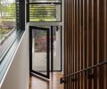 In the entry, a Bocci pendant illuminates the walnut floor and stair screen. The glass Marvin door is also from Cherry Creek Windows & Doors.