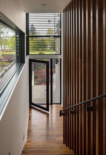 In the entry, a Bocci pendant illuminates the walnut floor and stair screen. The glass Marvin door is also from Cherry Creek Windows & Doors.