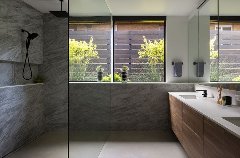 In the primary bathroom, porcelain tile called Marvel Stone Bardiglio wraps the walls. Leicht cabinetry forms the vanity, and the faucets are Brizo Vettis. The concrete floors have radiant heat.