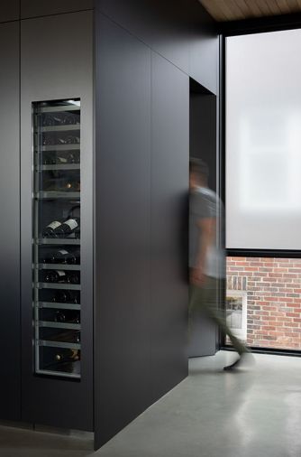 A Thermador wine column is unobtrusive in the sleek kitchen cabinetry from Leicht. The powder room door is accessed around the corner.